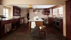 A burgundy and white kitchen with a wooden work table as a kitchen island