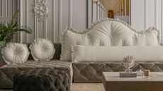 White WOWMAX ruffle headboard pillow styled atop a velvet grey button-tufted couch inside of a white living room featuring ornate molding and classical artwork
