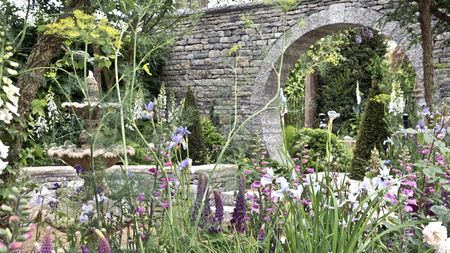An English regency garden with stone fountain, moongate and planting in foreground