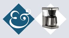 A stainless steel drip coffee maker on beside a blue diamond with an & sign in it. 