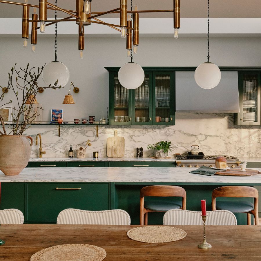 A family kitchen in an Edwardian home with green cabinets, marble countertops, and wooden accents