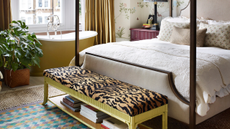 Ecclectic bedroom featuring a yellow tub, four-poster bed frame, and a tiger print-upholstered storage ottoman